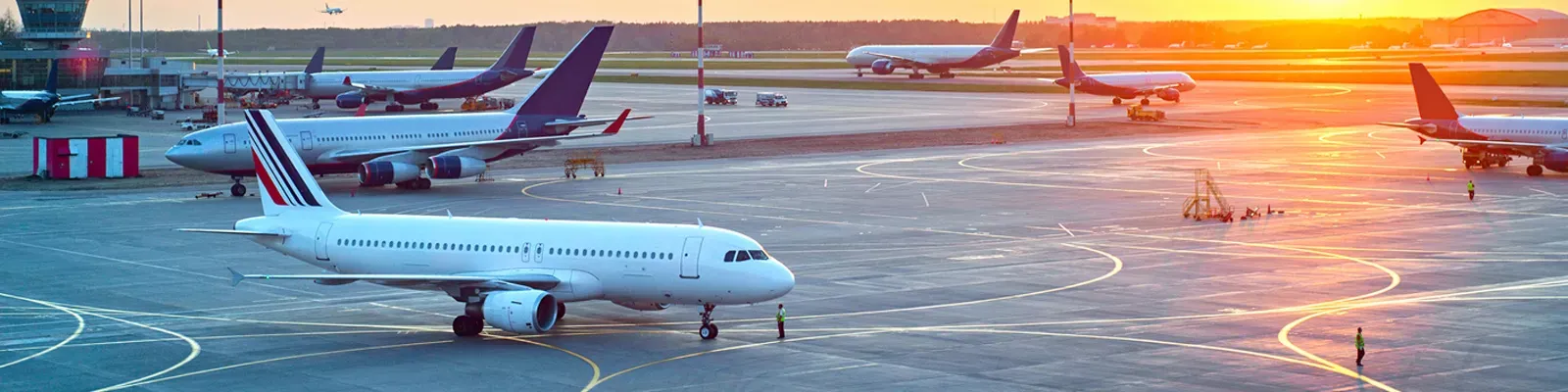 Flugzeuge auf dem Vorfeld eines Flughafens im Abendlicht – Flughafentransfer von Hanse Mondial