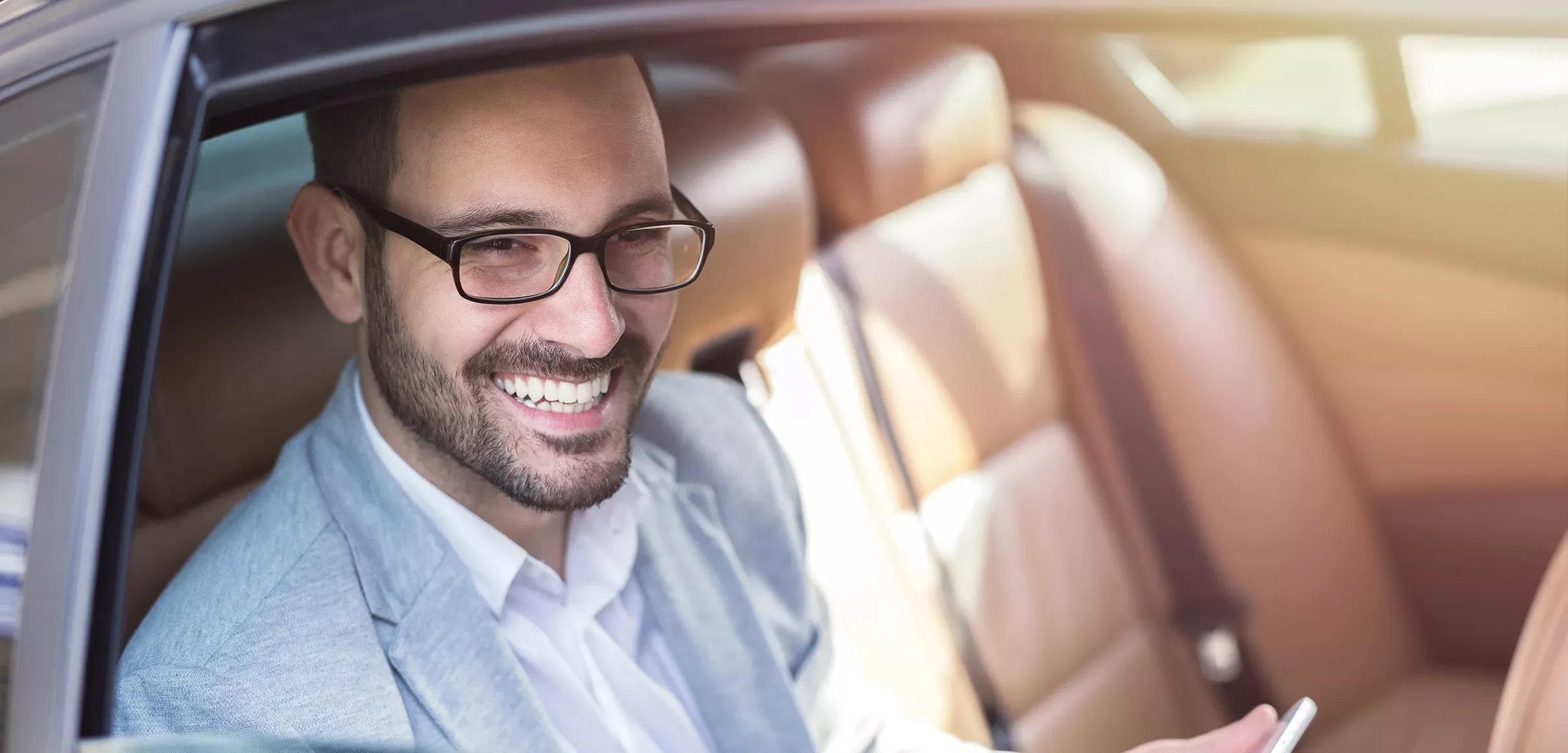 VIP-Fahrgast entspannt im Fond einer Limousine mit Chauffeur von Hanse Mondial