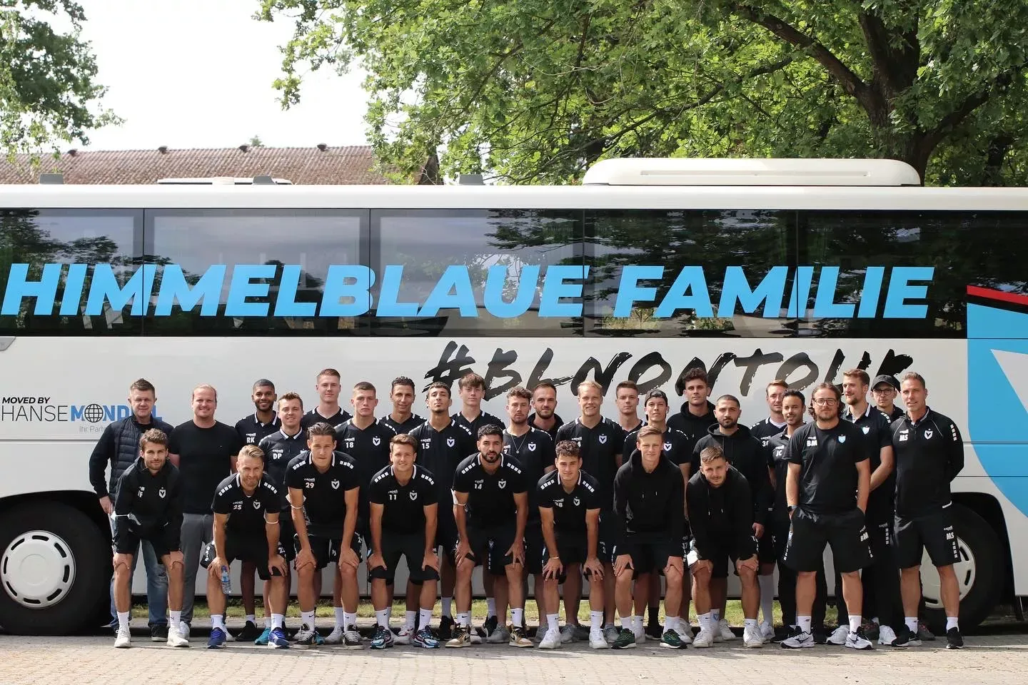 Mannschaft vor dem gebrandeten Hanse Mondial Vereinsbus „Himmelblaue Familie“