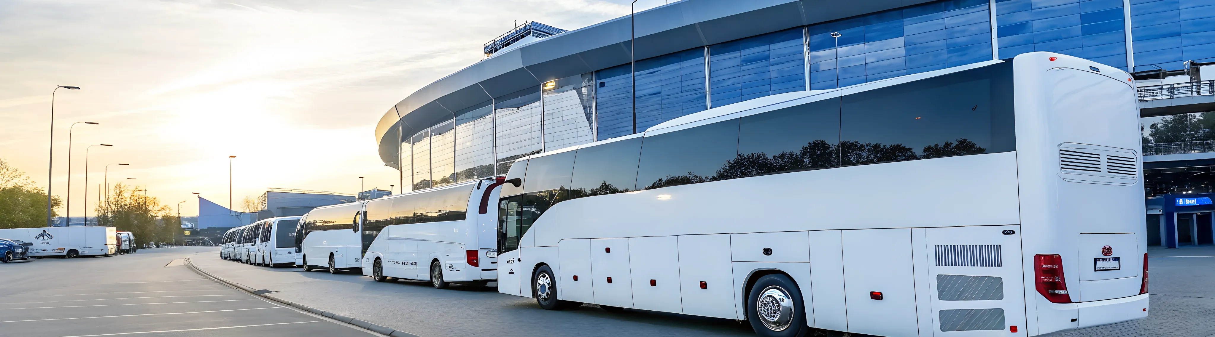 Weiße Reisebusse vor einer großen Stadion-Arena