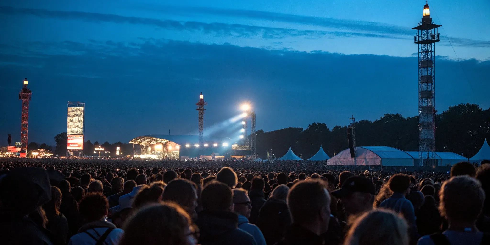 Festival crowd at night in front of a distant illuminated stage