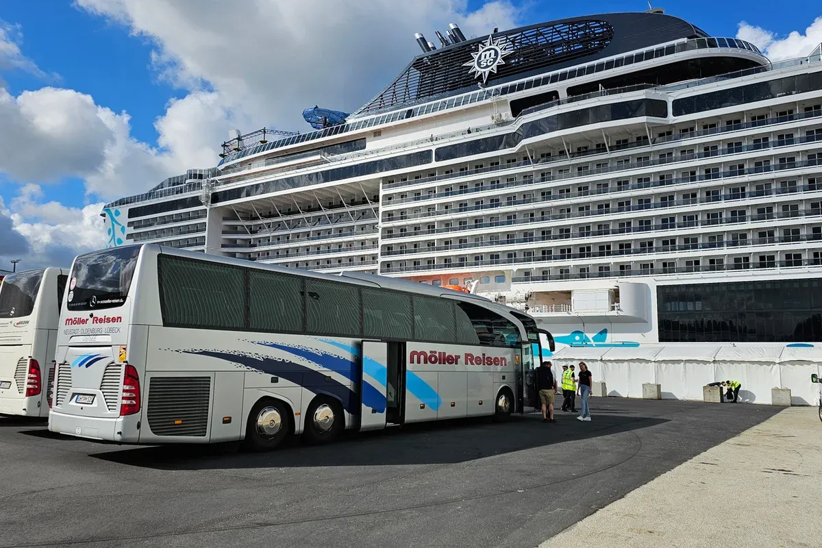 Reisebus vor einem Kreuzfahrtschiff im Hafen