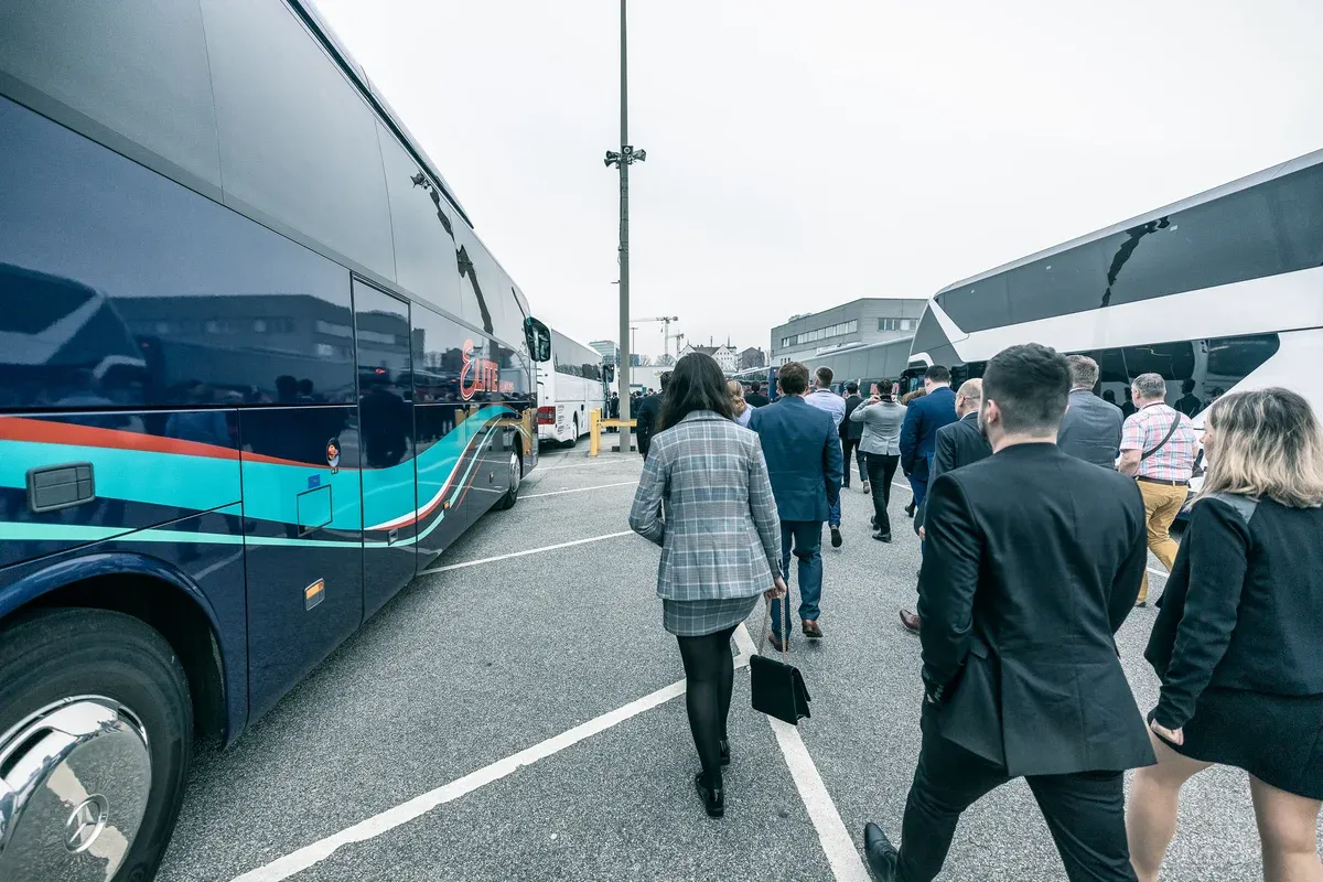 Event-Gäste gehen zwischen Reisebussen zum Einstieg