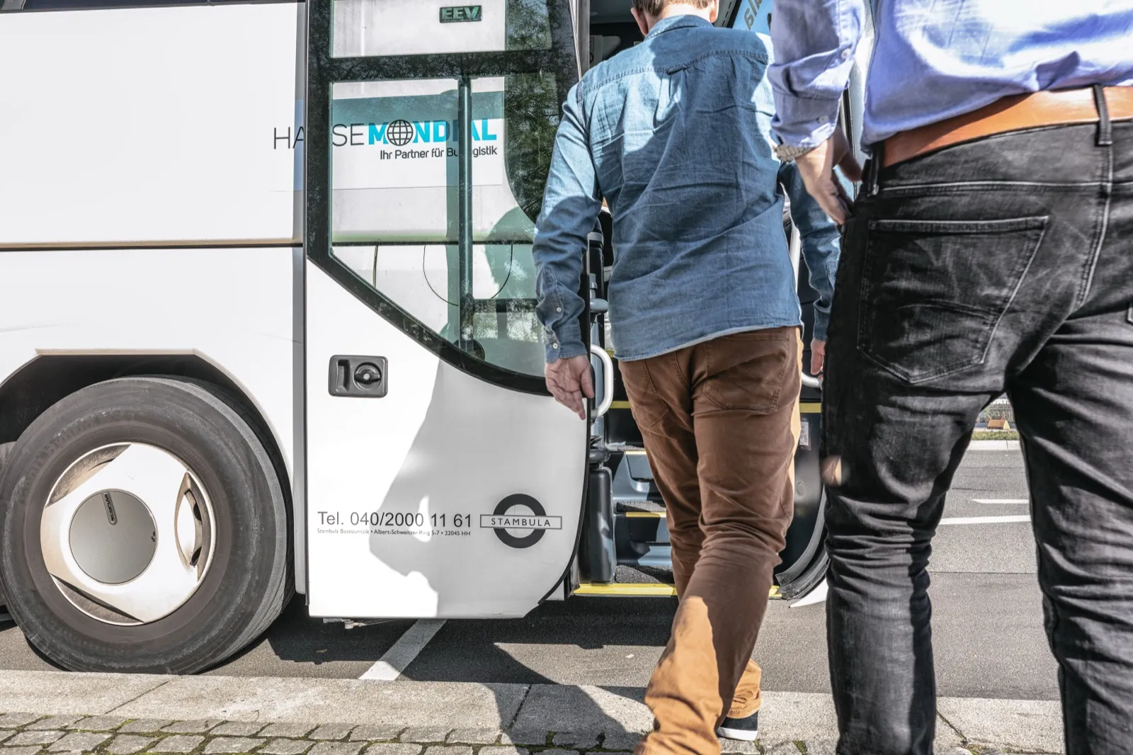 Fahrgäste steigen in einen beschrifteten Hanse-Mondial-Reisebus ein – geprüfte, professionelle Buspartner